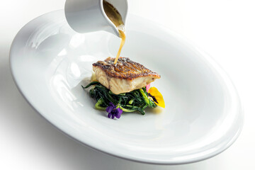 Plate with sea bass steak on green herbs with smoked tea