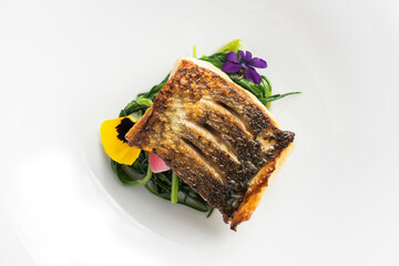 Plate with sea bass steak on green herbs