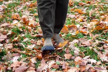 the feet of a teenager walk through the fall foliage