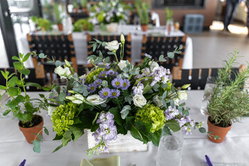 Green and purple floral bouquet as the table center piece at a bridal shower brunch. Each bouquet is flanked by smaller greens such as sage in pots.