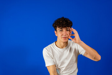 Naklejka premium Funny charismatic full man in white t-shirt with curly hair on blue background with pensive face. Isolated