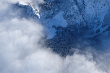 Bird's ey view of winter landscape with mountains, forest and clouds