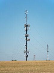 Large telecommunication tower with microwave links and cellular network antennas against blue sky.