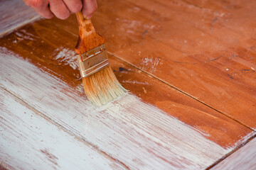 Mano con pincel pintando la mesa de madera