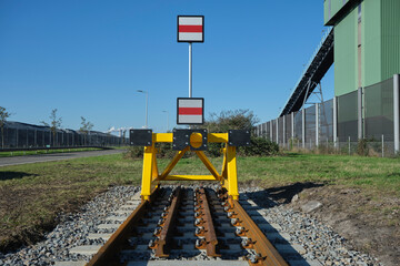 A yellow buffer stop, also called bumper or stopblock, marking the end of a train track. It's...