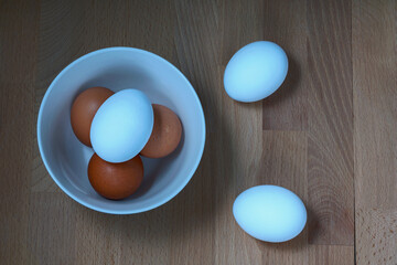 several fresh chicken eggs in a ceramic cup on a wooden background. Healthy eating concept