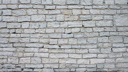 old brick wall made of limestone blocks of different sizes as the background