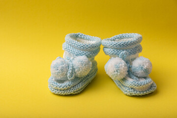 homemade knitted shoes for newborn boys on yellow background
