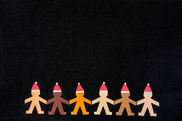 Multiracial human paper chain wearing Santa's hats accompanied by some black copy space to greet...