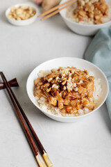 Sichuan dish Kung Pao. Chicken fillet in rice sauce. Close-up, with chopsticks, Vertical on a light background.