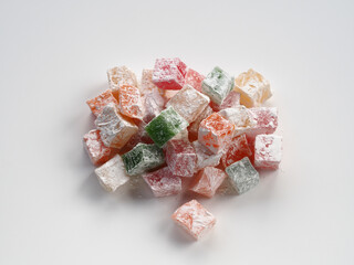 Isolated cubes of yellow, green, pink fruit Turkish delight with powdered sugar on a white background, flat layout. Delicious natural confectionery lukum for dessert