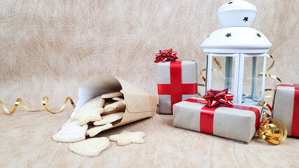 a white candle holder, Christmas cookies in eco-packaging and gift boxes packed in natural-colored paper and wrapped with red ribbon. preparing for the celebration of Christmas