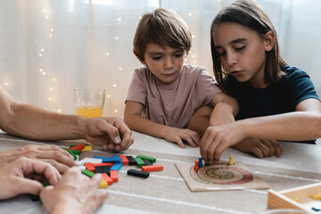 Fototapeta premium Happy family having fun playing board games with kids together at home - Focus on girl face