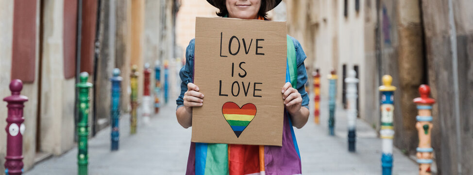 Gay woman holding lgbt banner with rainbow flag - Focus on lesbian girl cartel