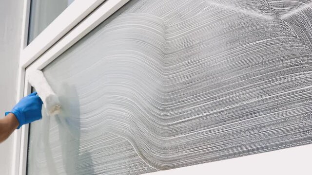 A professional worker washes windows with special products. Cleaning service
