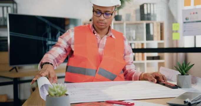 Attractive concentrated professional multiethnic male engineer in vest and helmet browsing paper project of future building in modern design office,slow motion