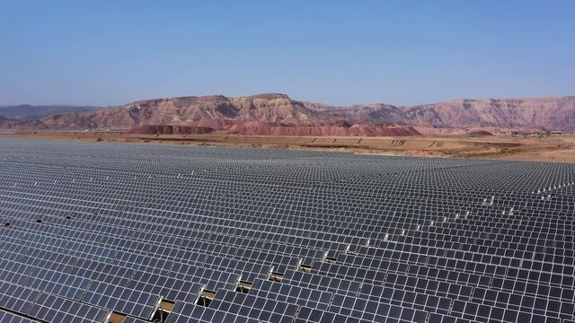 Aerial View of Solar Panel Park or farm Solar panels in the desert among the mountains. Drone Aerial Shot Of Power Station Over Landscape On Sunny Day Against Sky at the Negev, Israel.