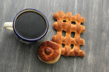Hot coffee in a blue artisan cup accompanied by delicious, fresh and fluffy Mexican sweet bread: biscuit, croissant, grill, pancha eye and worm
