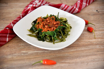 Water Spinach with spicy sauce, served on white plate. 