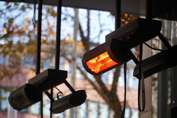Gas terrace heater or radiant heater under the high roof of a public café. Inefficient and...