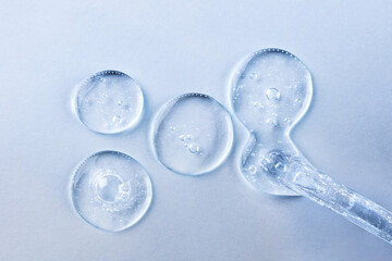 Transparent gel or serum pipette with drops on light background. Cosmetics concept with fluid.
