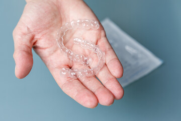 Hand holding transparent aligners. Invisalign orthodontics concept