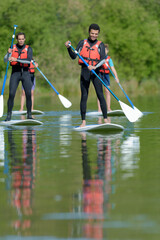 people with stand up paddle board sup on river - obrazy, fototapety, plakaty