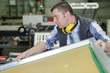 workman lifting awkward object in a factory