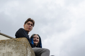 A man and a woman embrace sitting on a concrete parapet.