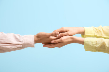 Woman holding man's hand on blue background