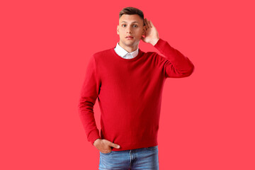 Young man trying to hear something on color background