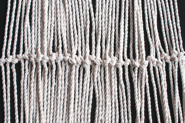 Macrame ornament from white natural cotton threads on a black background
