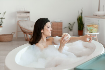 Naklejka premium Relaxed young woman taking bath with loofah at home