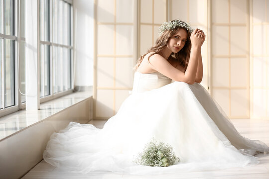 Beautiful bride with bouquet of flowers at home