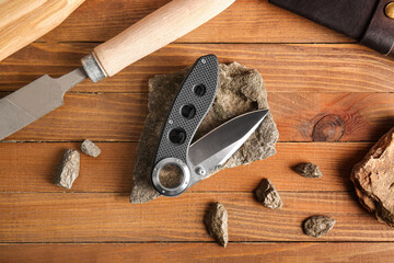 Folding pocket knife with rubberized handle on wooden table