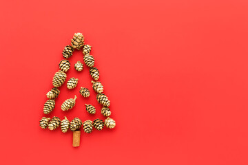 Christmas tree made from golden cones on a red background. Top view, copy space for text. Minimal Christmas concept