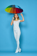 fashionable woman with umbrella rainbow colors posing blue background