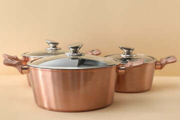 New steel cooking pots with glass ladle on light background