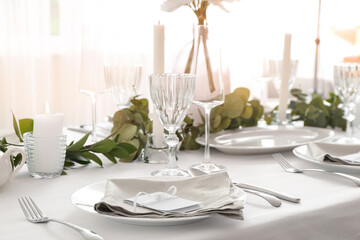 Beautiful table setting for wedding celebration with burning candles in restaurant