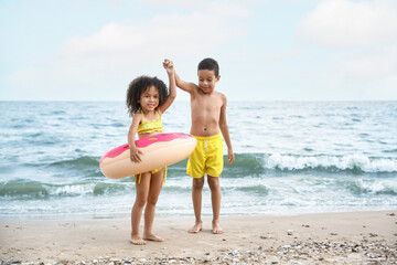 African-American children with inflatable ring on sea beach