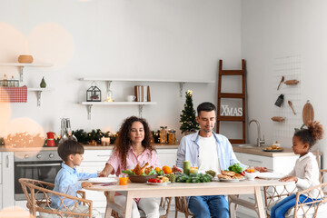 Happy family praying before having Christmas dinner in kitchen