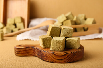 Board with tasty hojicha marshmallows on color background, closeup