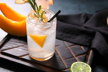 Wooden board with glass of tasty melon cocktail on table, closeup