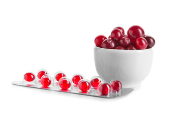Blister package with cranberry pills and bowl of berries on white background