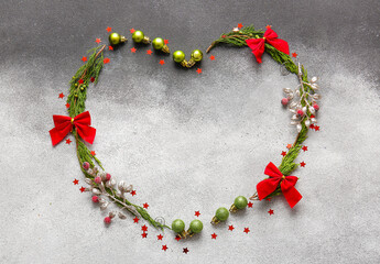 Heart made of Christmas decor with coniferous branches on black and white background