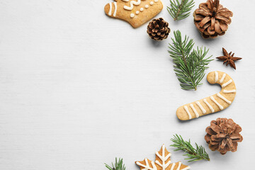 Fir tree branches, pine cones, anise and Christmas cookies on light wooden background, closeup
