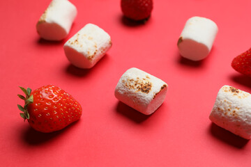 Tasty grilled marshmallows and strawberries on red background