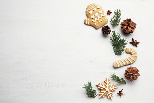 Fir tree branches, pine cones, anise and Christmas cookies on light wooden background