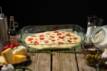 Italian focaccia bread prepared for baking in a glass form. Ingredients. There are no people in the photo. Cooking blog, step by step recipe, cookbook, restaurant, hotel, bakery.