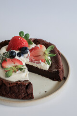 Fresh Delicious chocolate flourless cake with strawberry, blueberry and whipping cream on white background. Homemade bakery concept. Ready for eating.
